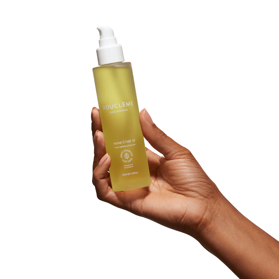 Hand houdt Bouclème Revive 5 Hair Oil, 100 ml vast, CG-vriendelijke olie voor volume en glans in krullend haar.
