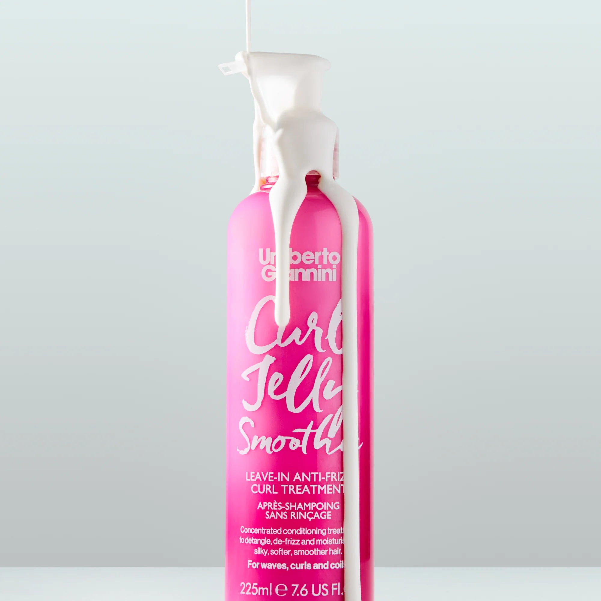 Umberto Giannini Curl Jelly Smoothie fles met conditioner die uit de pomp stroomt, benadrukt de rijke, hydraterende formule voor krullen 2a-4c.