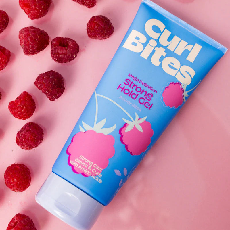Curl Bites - Mega Definition Strong Hold Gel 200ml op roze achtergrond met verse frambozen, styling gel voor maximale kruldefinitie.