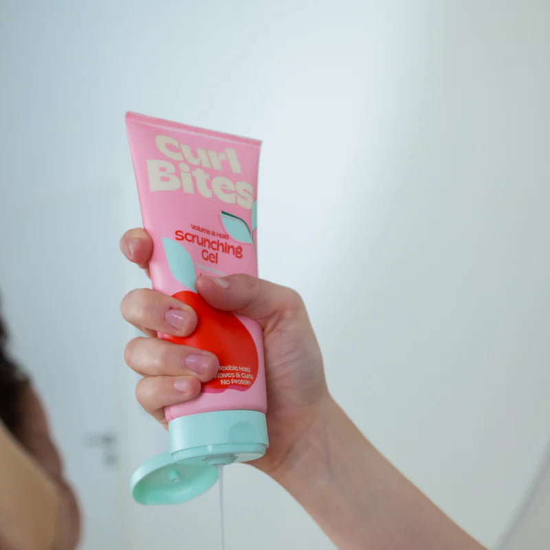 Hand knijpt Curl Bites Volume & Hold Scrunching Gel 200ml uit tube tijdens styling, ideaal voor natuurlijke kruldefinitie zonder proteïne.