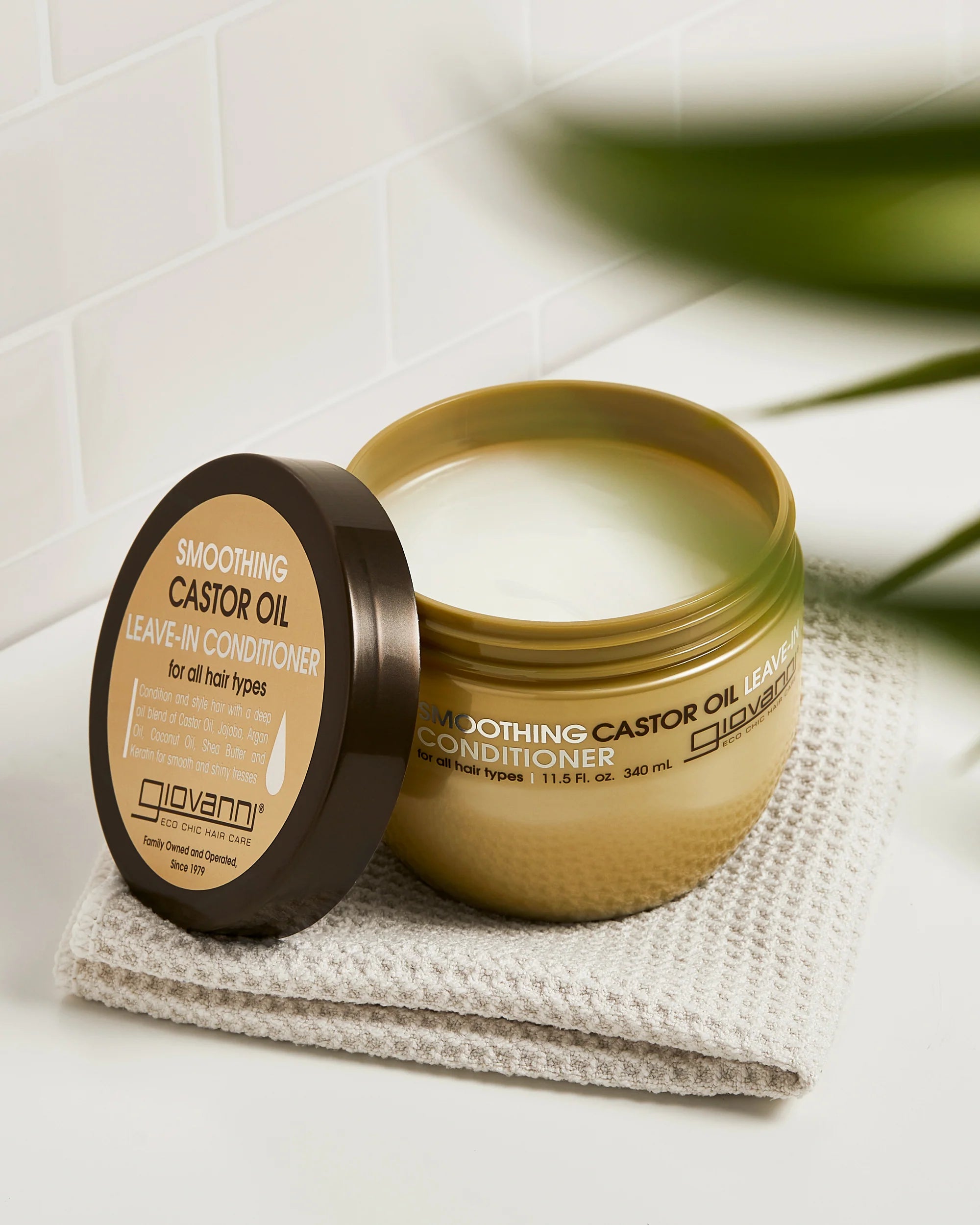 Open Giovanni Cosmetics Castor Oil leave-in conditioner -340ml op handdoek, romige textuur zichtbaar. Perfect voor glad, gevoed en gezond haar.