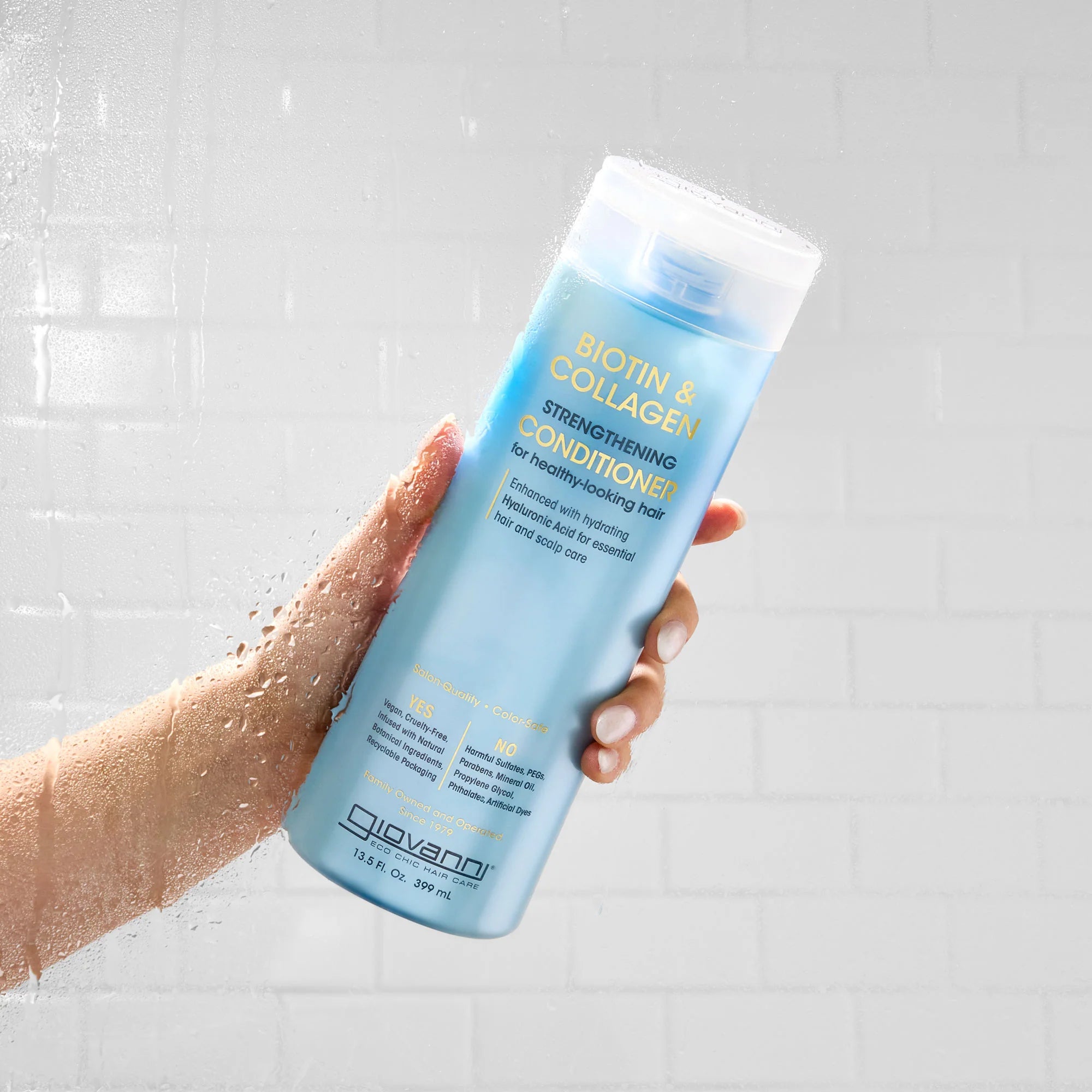 Hand houdt Giovanni Cosmetics - B&C Strengthening Conditioner - 399ml vast onder de douche, perfect voor gezonde krullen en CG-haarverzorging.