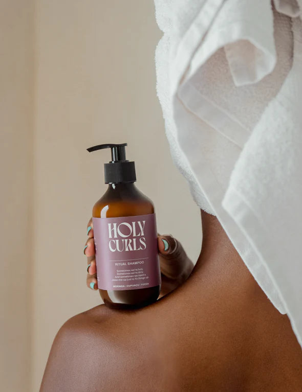 Persoon met handdoek houdt Holy Curls Shampoo, 300 ml, vast op schouder, perfect voor natuurlijke krullenverzorging.