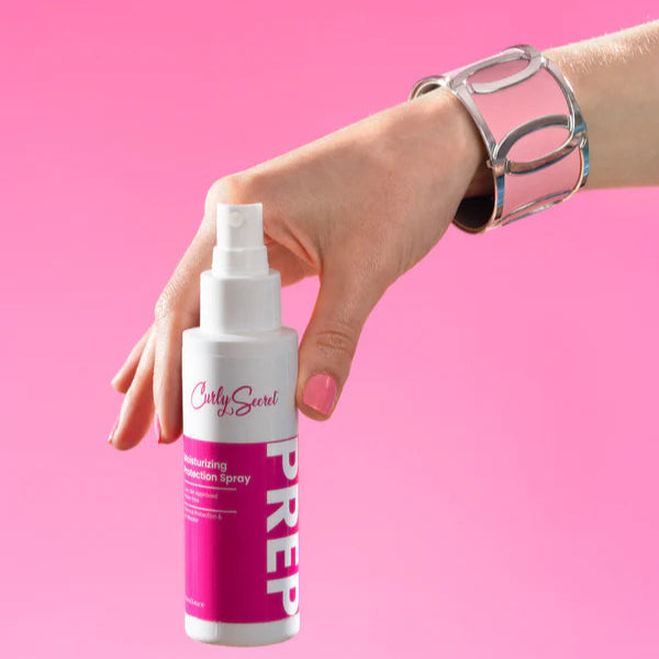 Hand houdt Curly Secret Moisturizing Protection Spray -UV Blocker 100ml haarspray vast, perfect voor hittebescherming en haarverzorging.