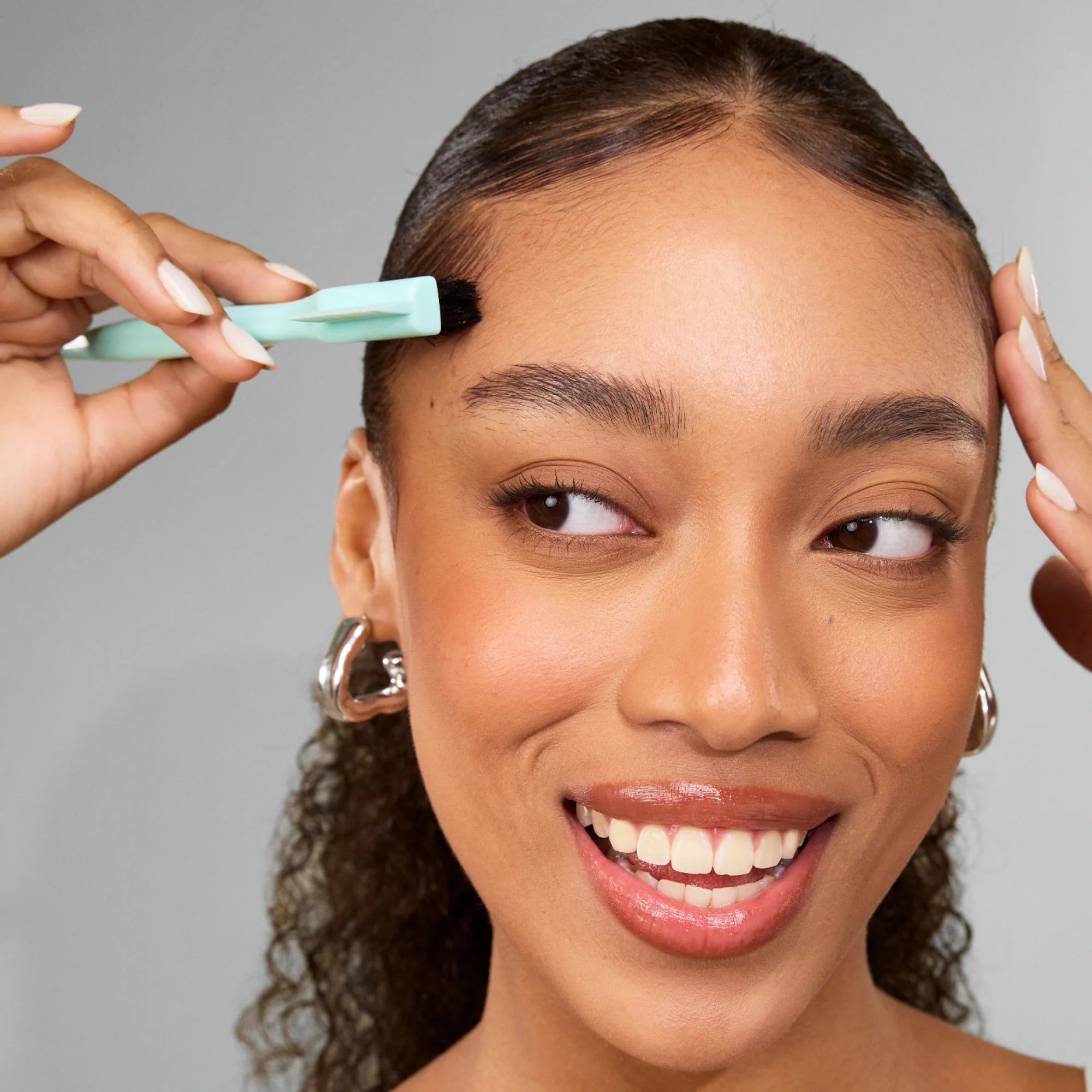 Vrouw gebruikt Umberto Giannini Strong Curls Slick Gel voor strakke edge-styling, perfect voor natuurlijke krullen en gladde looks.