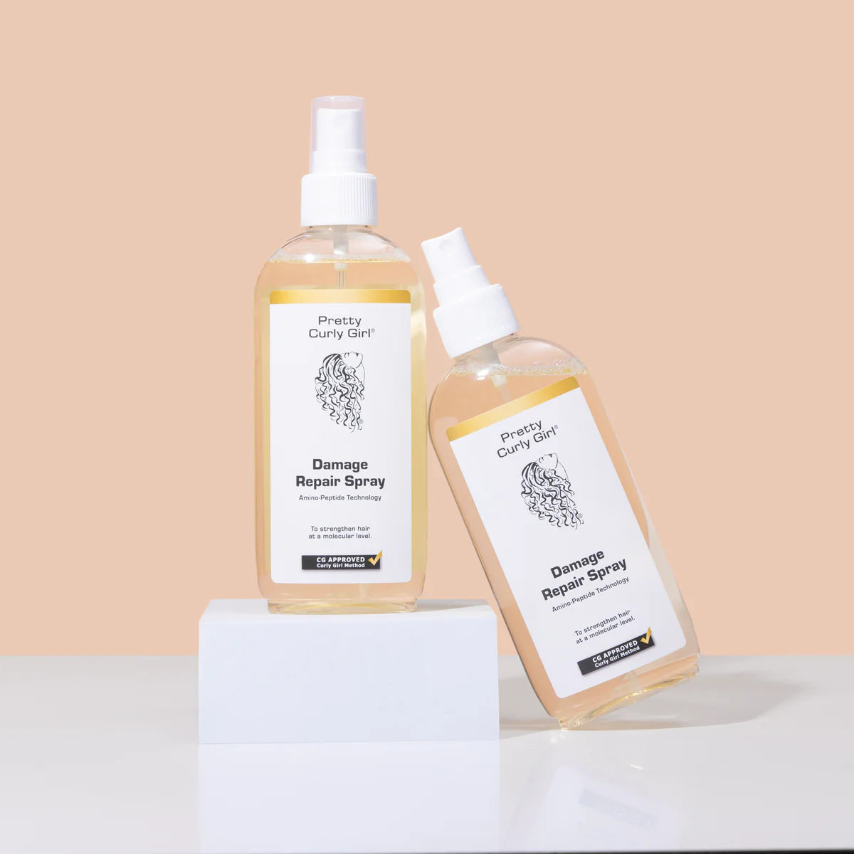 Twee flessen Pretty Curly Girl Damage Repair Spray haarspray gepresenteerd op witte blokken tegen een beige achtergrond, CG-goedgekeurd product.