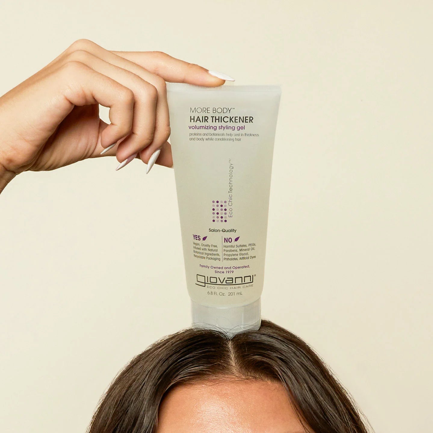 Giovanni Cosmetics - More Body Hair Thickener 200ml haargel wordt vastgehouden boven hoofd met bruin haar, perfect voor zichtbaar voller haar.