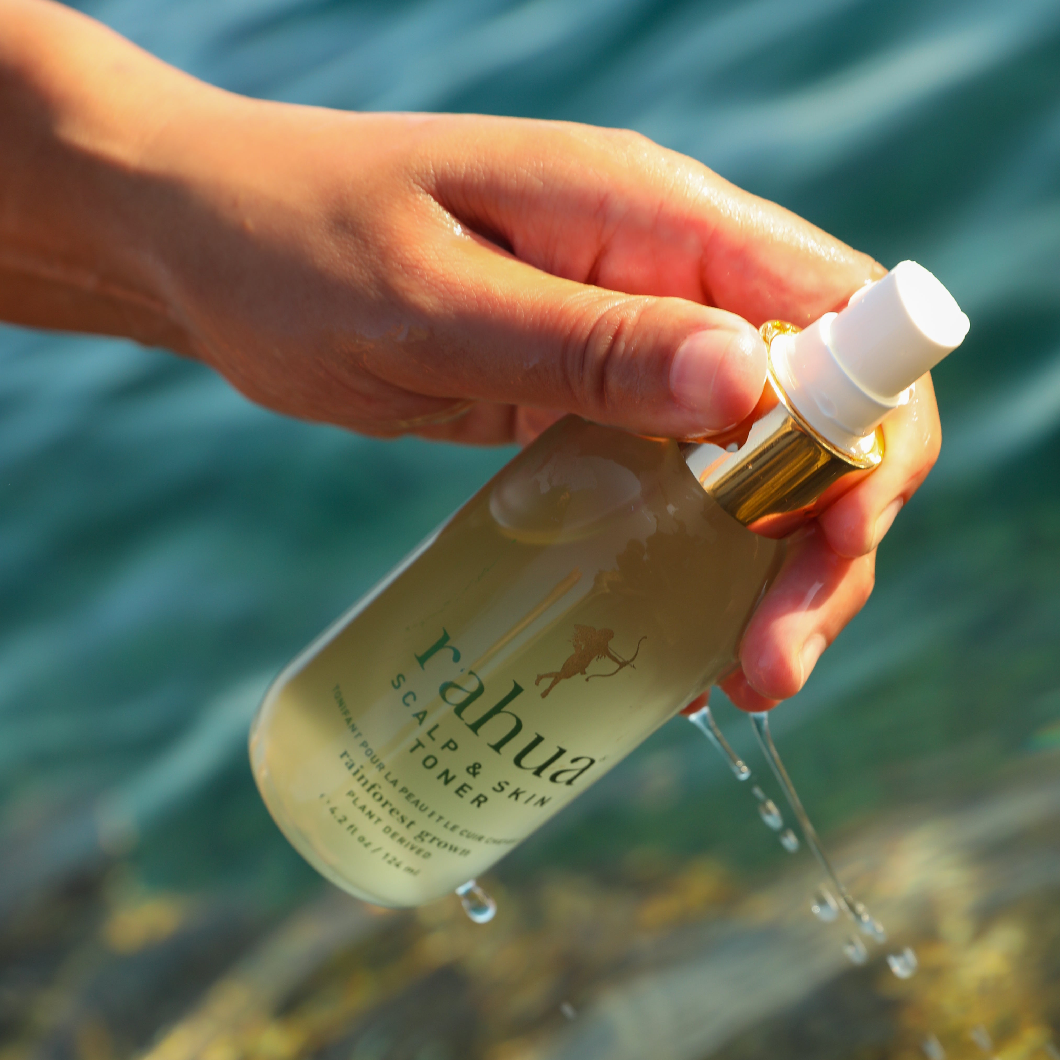 Rahua Scalp & Skin Toner – Natuurlijke haartoner in hand boven water, benadrukt hydraterende werking en tropische oorsprong van ingrediënten.