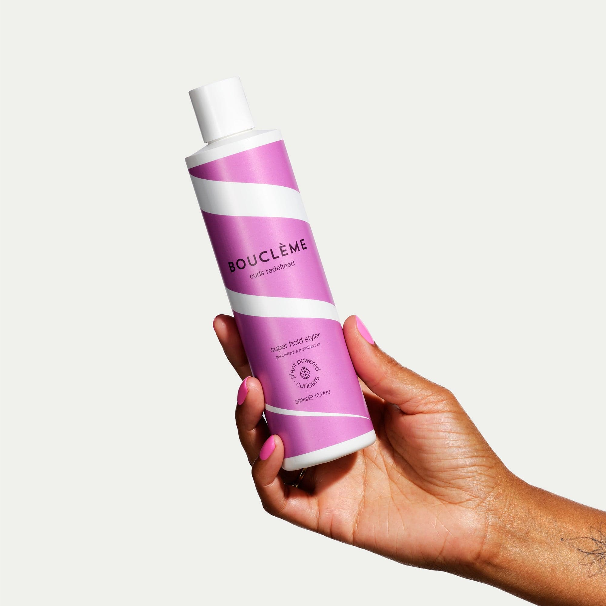 Hand houdt Bouclème Super Hold Styler, 250 ml styling gel vast, ideaal voor het stylen van krullen met langdurige fixatie.