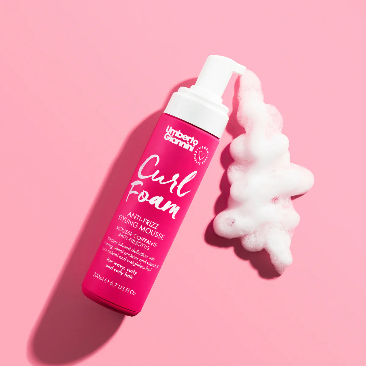 Umberto Giannini Curl Foam mousse met proteïne op roze achtergrond, toont luchtige textuur voor flexibele hold en volume bij krullend haar.